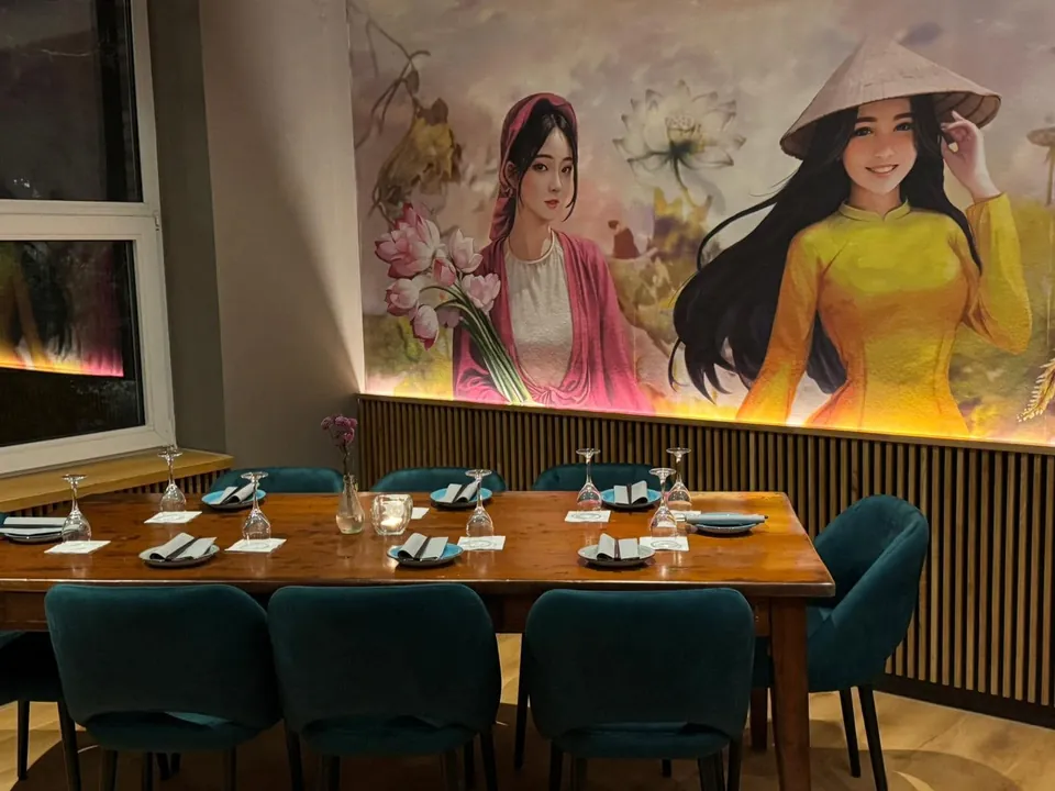 Gastraum mit gedeckter Tafel, petrolfarbenen Samtstühlen und Wandmalerei